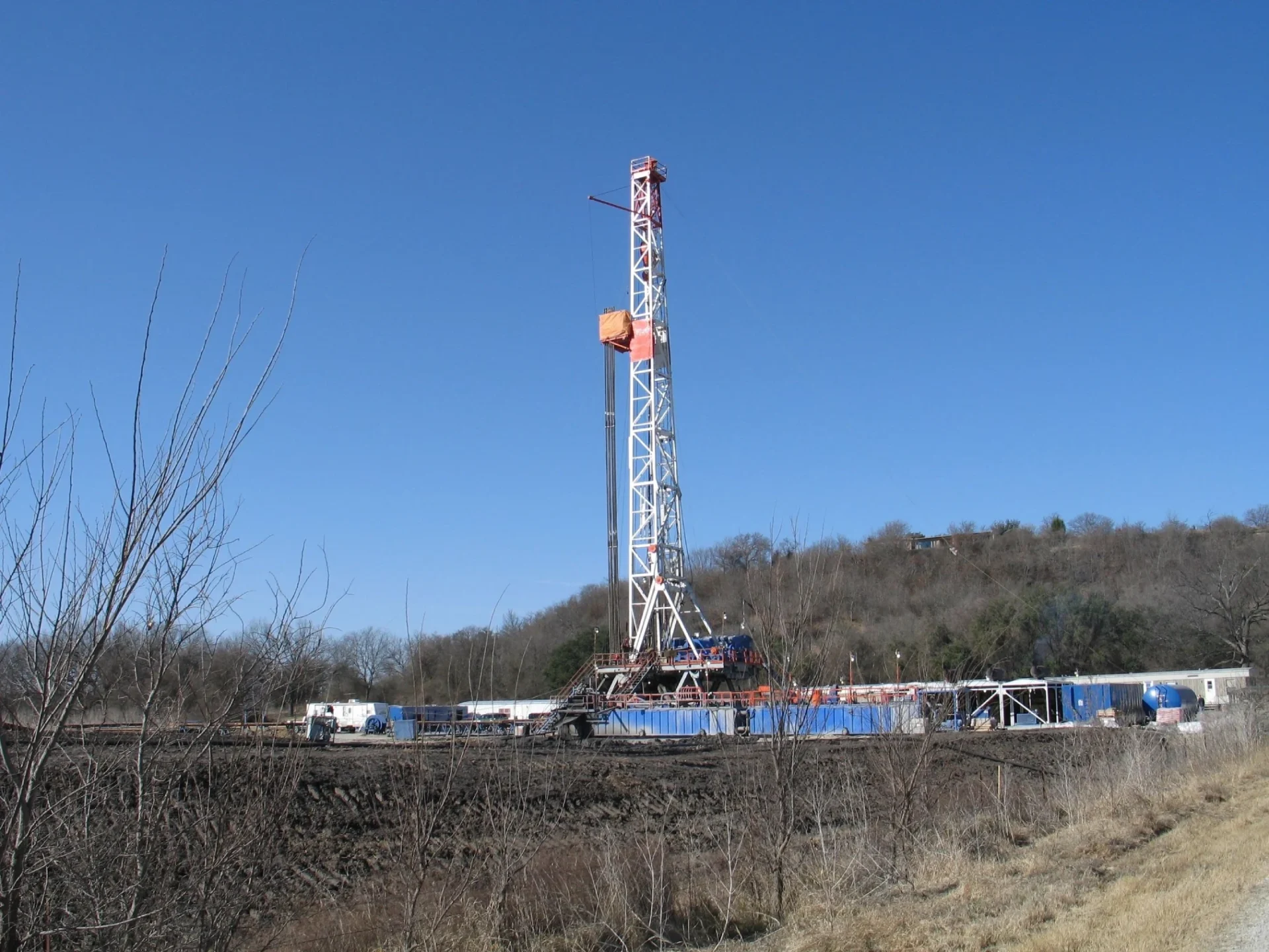 A drilling rig is on the side of a train track.